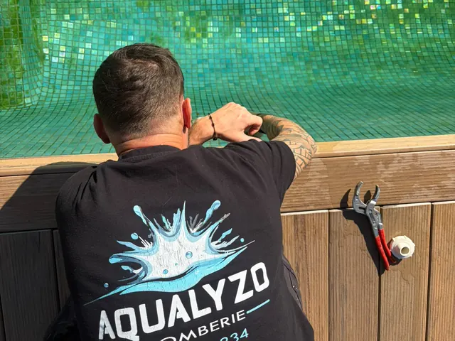 Anthony DINNAT contrôle un skimmer au bord d'une piscine carrelée